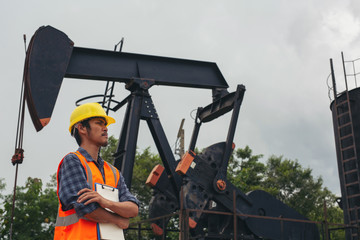Workers standing and checking beside working oil pumps.