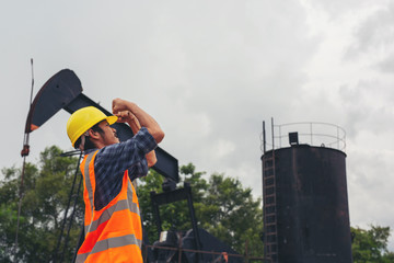 Workers standing and checking beside working oil pumps.