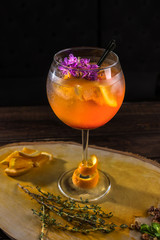 Close-up alcoholic cocktail with orange on wooden cross section of trunk tree decorated with mint, strawberry and orange