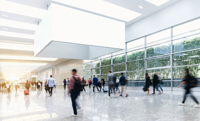 Many anonymous people are walking around advertising posters at a trade fair, copyspace for your individual text.