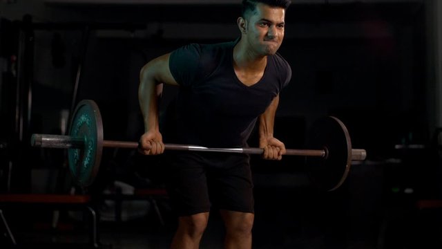Closeup shot of a young Indian man doing barbells deadlift exercise . 