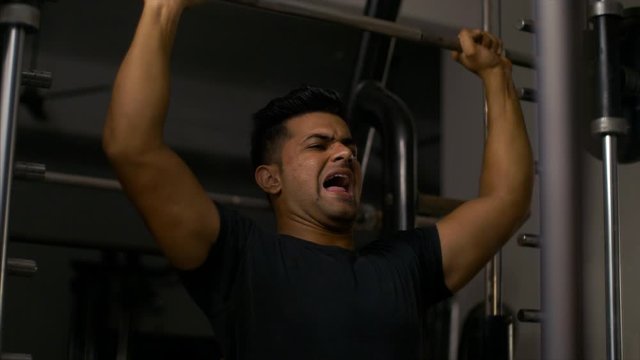 Indian male bodybuilder doing workout exercise with the barbell weight machine. 