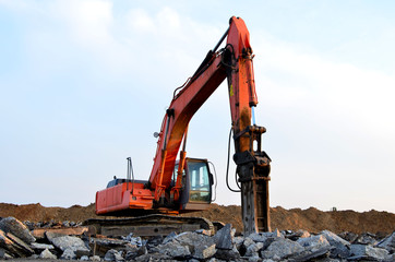 Crawler excavator with hydraulic hammer for the destruction of concrete and hard rock at the construction site. Salvaging and recycling building and construction materials, concrete demolition waste