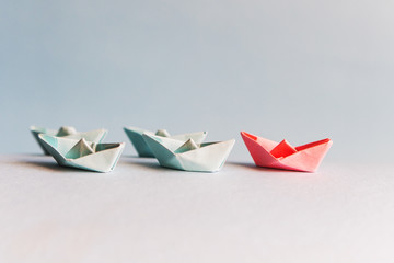 several blue and one red paper boat. The concept of leader, success.