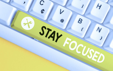 Conceptual hand writing showing Stay Focused. Concept meaning Be attentive Concentrate Prioritize the task Avoid distractions White pc keyboard with note paper above the white background
