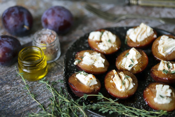 Baked plums with feta cheese and thyme. Keto friendly. Selective focus. Macro.