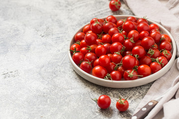 Tiny cherry tomatoes (ciliegini, pachino, cocktail). group of cherry tomatoes on a gray concrete background. ripe and juicy cherry tomatoes