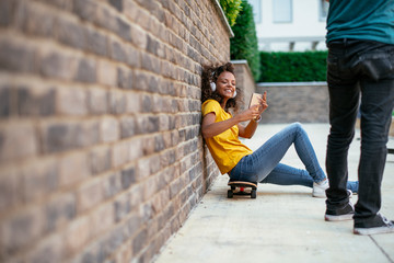 Fototapeta na wymiar Beautiful afro girl taking selfie while sitting on skateboard