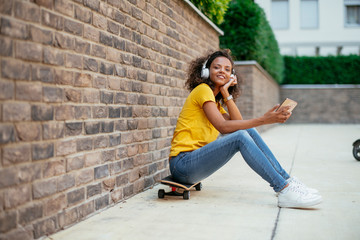 Fototapeta na wymiar African skater girl using phone