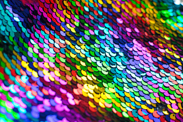 Texture of rainbow shiny sequins. Fashionable bright fabric with sequins. Selective focus.