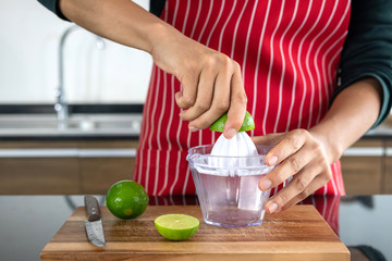 Young men squeezing lemonade in the kitchen