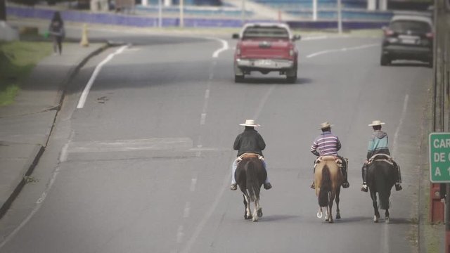 Three horsemen riding on the street of the city. Typical Gauchos riding horses on the highway. Slow motion