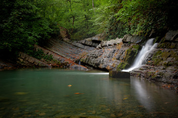 waterfall in the forest. Waterfall flows into a small lake.