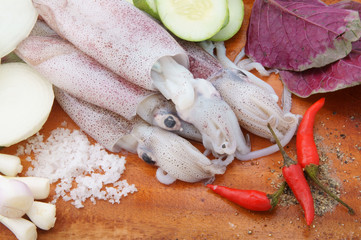 Seafood cooking concept, squids with vegetables on wooden background