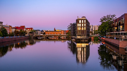 Fototapeta na wymiar The river Odra at sunrise with modern building in Wroclaw, Poland. Viwe from university bridge.