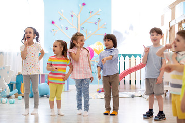 Preschool children standing on floor in kindergarten or day care centre. Emotional kids having fun indoors, playing games