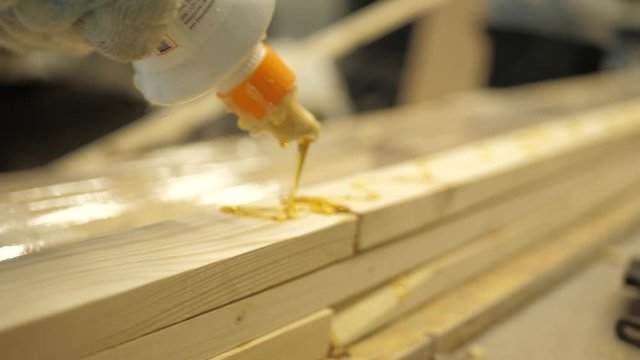 The master in the carpentry workshop glues the boards with special glue before pressing