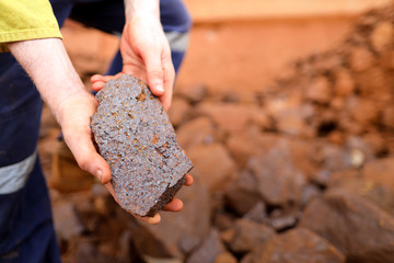 Close up picture of scientist geologist hands inspecting exploration on iron ore rock on open field...