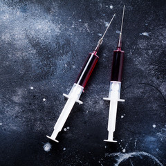 Syringe with blood on old concrete background. Square image. Top view.