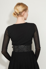 Cropped back view shot of a blond girl, posing on a white background. She is wearing black gown...