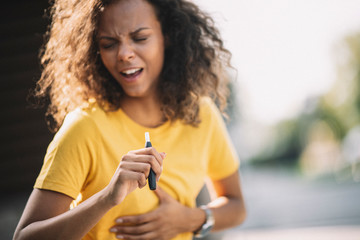 Afro girl smoking e-cigarette and coughing