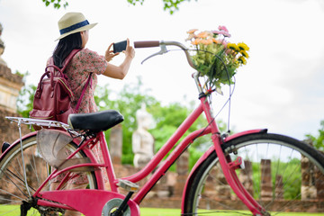 woman tourist enjoy riding local bicycle to see the historic park of Thailand, exciting takes photo to explore the wonderful place of sightseeing