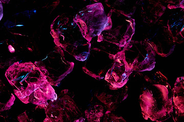 top view of transparent ice cubes with purple lighting isolated on black