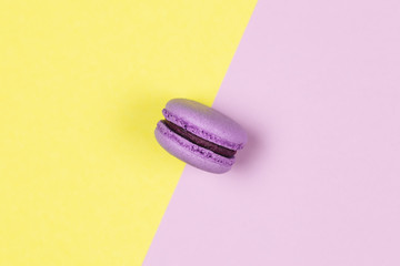 Purple french macaron on a yellow and purple background.