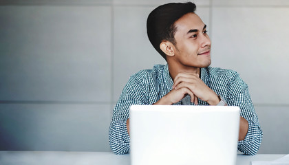 Happy Young Businessman Working on Computer Laptop in Office. Smiling and looking away