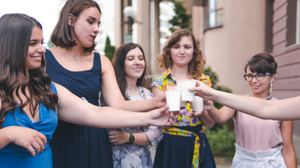 Group of girlfriends toasting with champagne in paper glass. Young people celebrating with champagne at party outdoors. Concept of hen-party