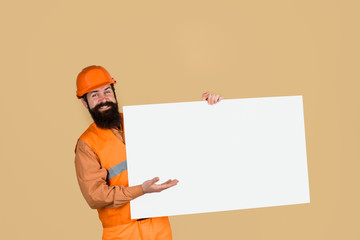 Construction worker, engineer, architect with blank board. Builder, repairman in protective helmet holds empty board with space for text. Man builder holds advertising banner, billboard, sign board.