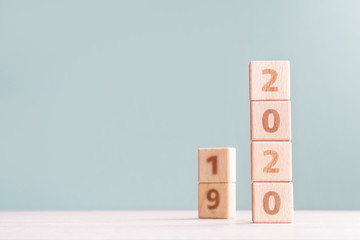 Abstract 2020 & 2019 New year countdown design concept - wood blocks cubes on wooden table and low saturation green background, close up, copy space.