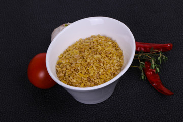 Raw bulgur in the bowl with tomatoes and garlic