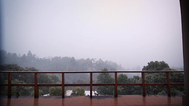 Beautiful snow falling from the veranda w/ mountain background, wide angle clip, Patagonia, Argentina
