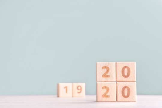 Abstract 2020 & 2019 New year countdown design concept - wood blocks cubes on wooden table and low saturation green background, close up, copy space.