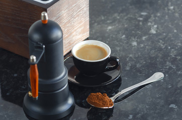Coffee maker Type geyser and black colored coffee cup, with coffee beans and freshly ground coffee in a spoon