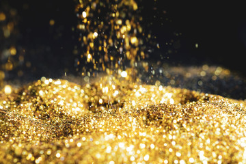 Sprinkle glitter gold dust sand in the dark textured abstract background elegant for Merry...