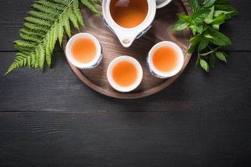 Tea ceremony. Three cup of green tea with mint and kettle on dark background. Chinese concept. View from above. Asian still life.