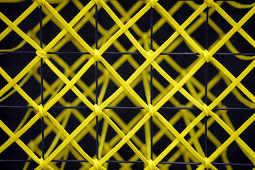 Yellow rope tied to a black steel grill, Abstract texture background