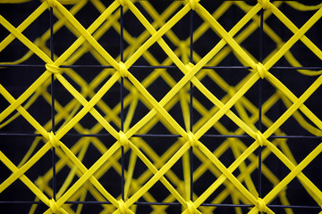 Fototapeta premium Yellow rope tied to a black steel grill, Abstract texture background