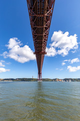 Under the bridge, calm river with sailing boats and a statue on top of the hill