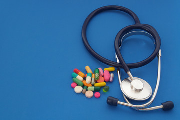 Stethoscope and many drugs and pills on blue background with space for text, healthcare and pharmaceutical concept