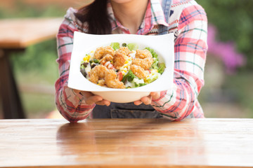 Asian woman enjoying her healthy salad with crispy salad in big white bowl on the table outdoor in garden