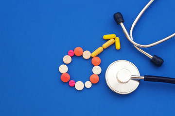 Male gender symbol made of tablets and pills with stethoscope on blue background with space for text.  Medicine for men concept.