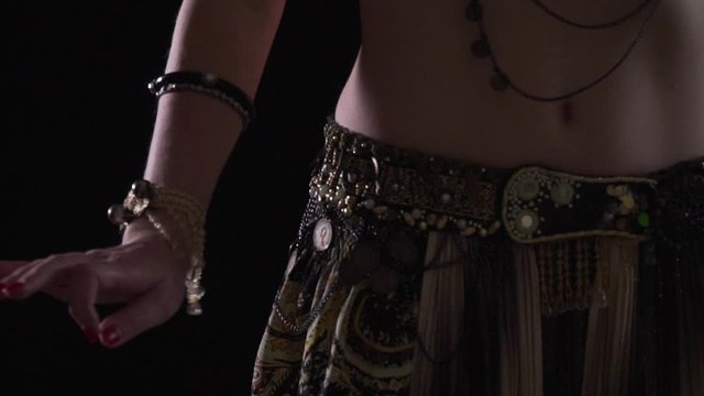 Close up of the body of a woman belly dancing wearing traditional dress