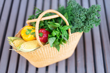 Girl holding basket with healthy organic vegetables, wooden background, copy space. Autumn harvest. Zero waste, plastic free concept. Sustainable lifestyle. Thanksgiving day