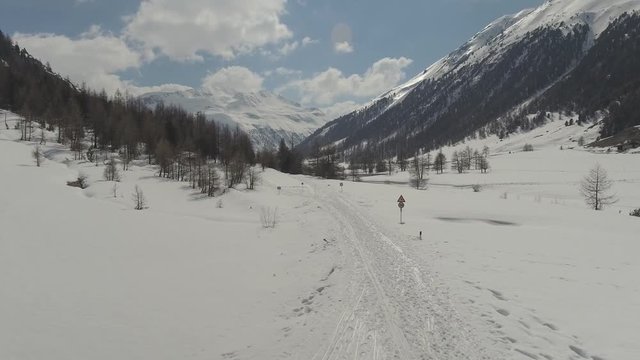 Ski tour and cross-country ski routes in Livigno, Italy in direction to Passo Forcola. Aerial reveal of a snowy valley during sunny day at the beginning of spring