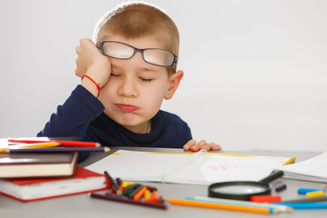 This boy is very tired of doing his homework, he fell asleep