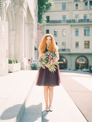 Fototapeta premium young beauty woman with flower buquet on the spring street. film analog photography