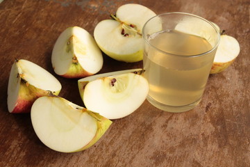 Fresh hot fruit juice in glass with apple pieces on wooden table